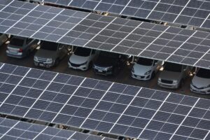 Solar panel carport covering parked vehicles in a car park, generating renewable solar energy while providing shaded parking for cars.